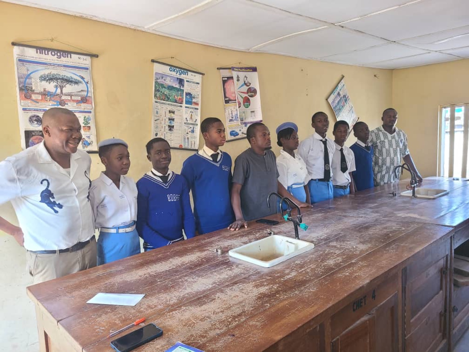 Secondary school students standing along a science bench.