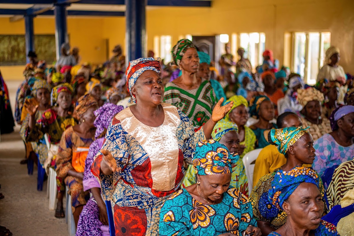 A woman standing to speak in a crowded hall.